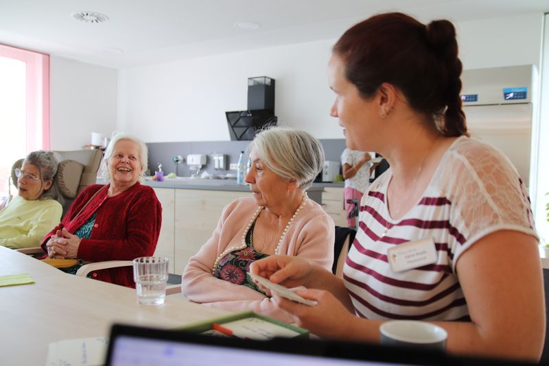 Eine Gruppe von Frauen sitzen an einem Tisch und unterhalten sich.