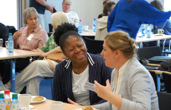 Zwei Frauen im Gespräch bei einer Konferenzrunde mit Getränken