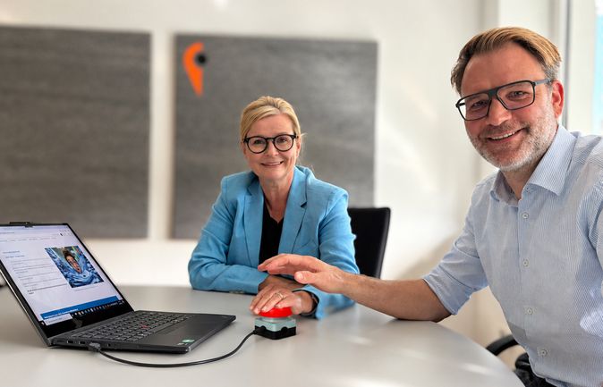 Pia Theresia Franke und Klaus Günthör starten mit einem Buzzer die digitale Gehaltsabrechnung