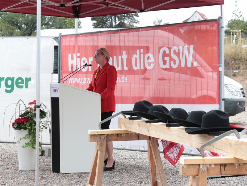 Rednerin spricht unter einem Pavillon vor Gästen des Richtfests.