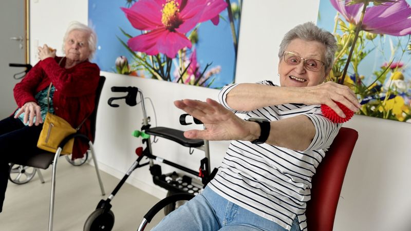 Ältere Frau massiert sich mit einem Massageball und lächelt dabei