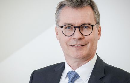 Porträt eines lächelnden Mannes mit Brille im Anzug