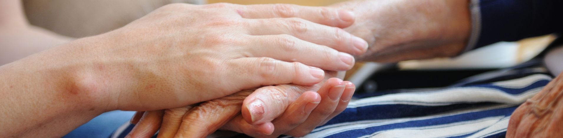 Jüngere Hand hält behutsam die Hand einer älteren Person