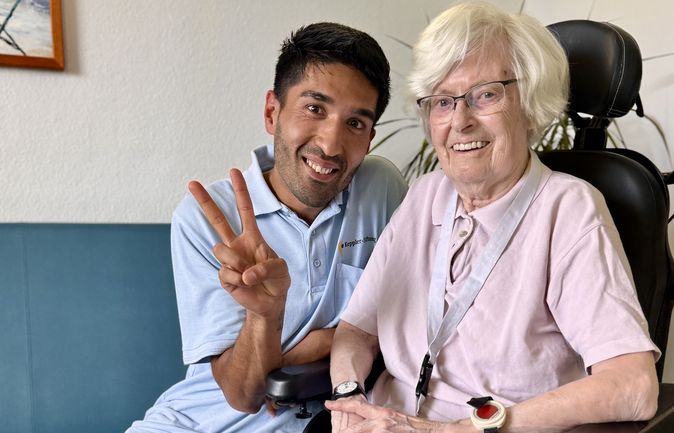 Junger Betreuer und ältere Frau im Rollstuhl als Lerntandem