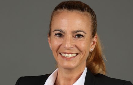 Lächelnde Frau mit Pferdeschwanz in weißer Bluse und schwarzem Blazer