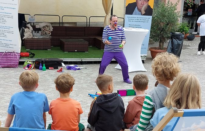 Clown mit bunten Bällen jongliert vor Kindern beim Weiler Strandsommer