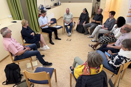 Mehrere Menschen im Stuhlkreis in Gesprächsrunde, ein Mann spricht