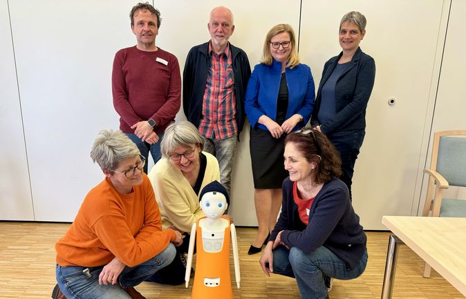 Sieben Personen versammeln sich um den Sozialroboter Noah